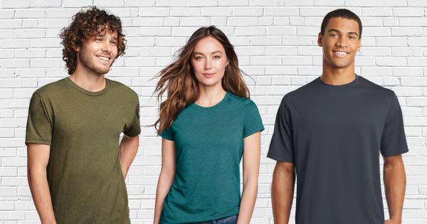 Image of three people in three different colored tees standing in front of a white brick wall. Olive green t-shirt, teal t-shirt, dark gray tee.